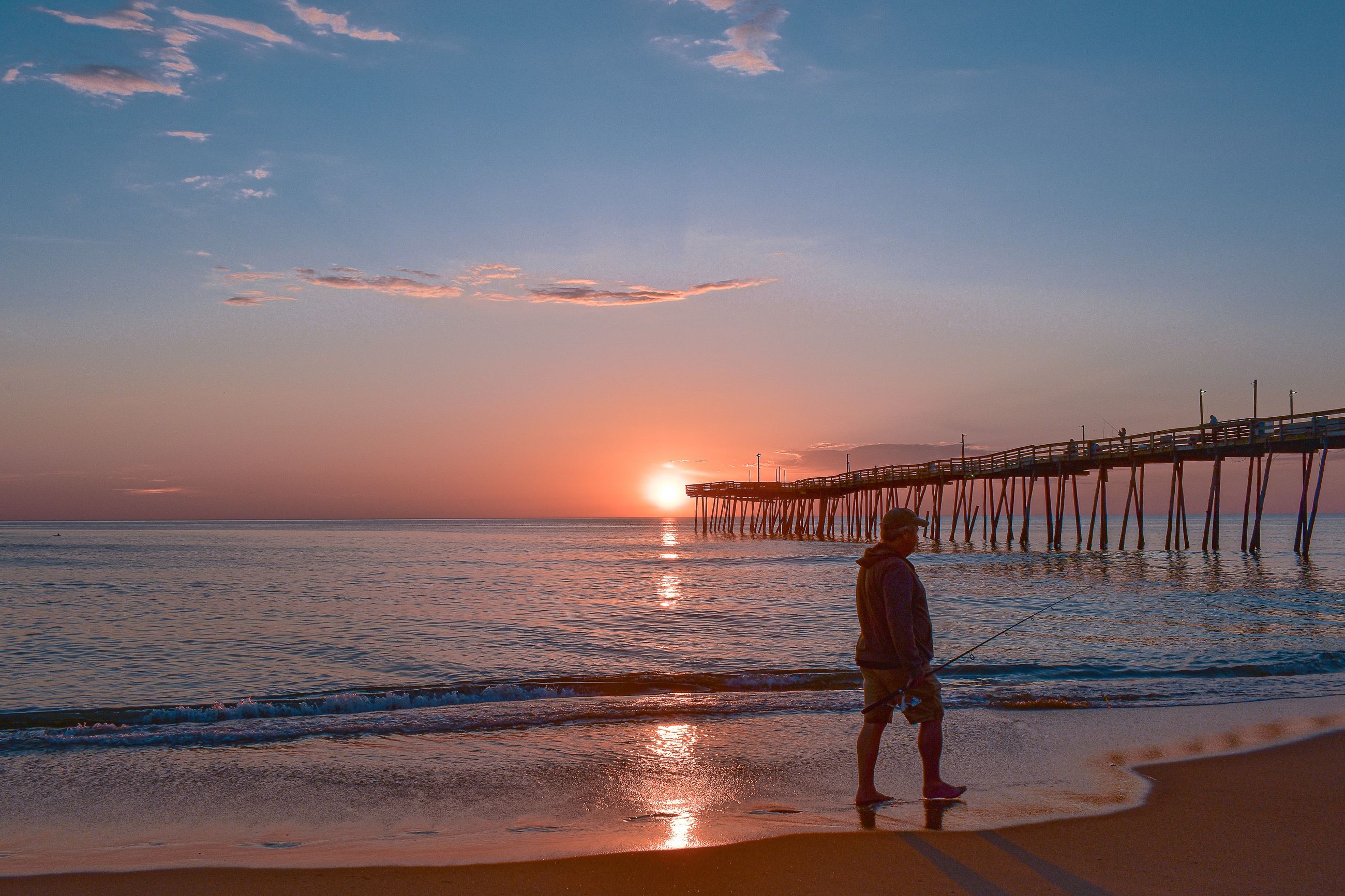 fisherman walking along the beach at dawn